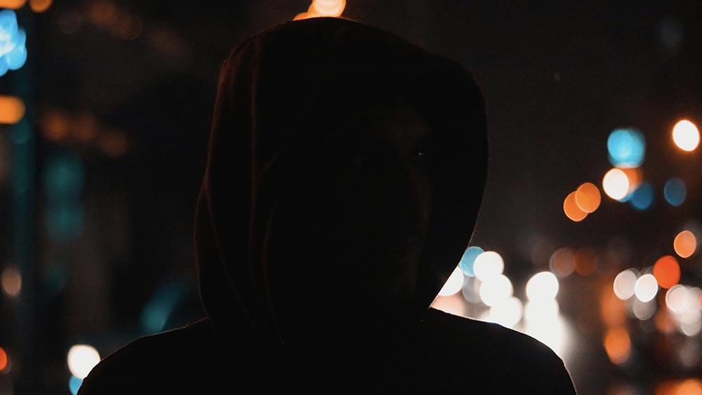 hooded man surrounded by lights